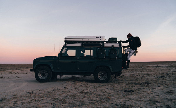A person carrying the Original Shadow Guide 31 while climbing up the roof ladder of a Jeep.